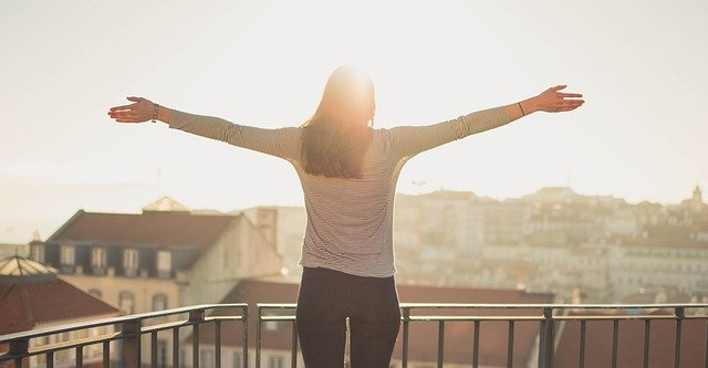 femme à son balcon ouvrant les bras au ciel